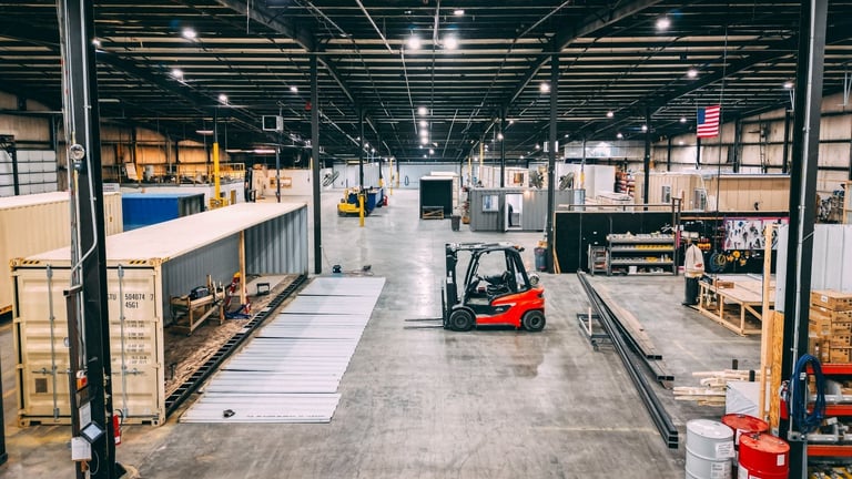 Warehouse interior with forklift loading shipping containers, industrial storage facility with cardboard boxes and equipment.
